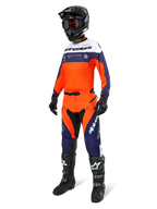 Pantalon Alpinestars Pro-Dura, pantalon de motocross et d'enduro, bleu navy, orange vif et blanc, porté avec une tenue de course complète comprenant un maillot assorti, un casque noir et des bottes noires, doté de panneaux durables et d'un marquage distinctif pour des performances tout-terrain