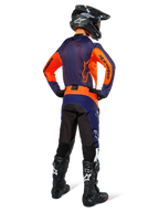Pilote de motocross de dos portant une tenue de course complète Alpinestars, maillot bleu navy et orange, pantalon Pro-Dura en Navy Hot Orange White, casque noir et bottes noires, ensemble professionnel de course tout-terrain