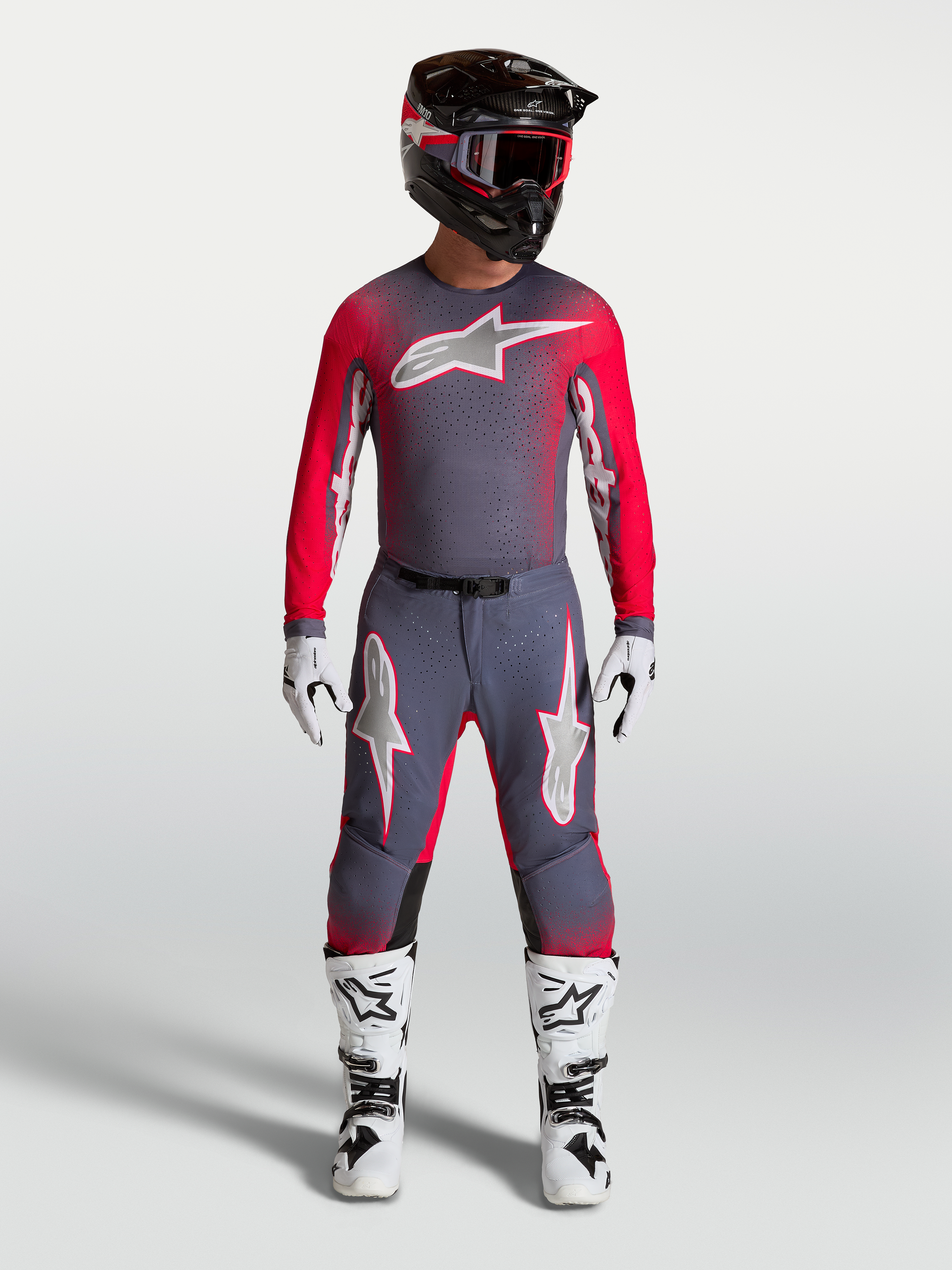 Alpinestars Supertech Hiten AFD Gear Set et Pantalon, tenue de motocross pour homme, gris et rouge fluo, avec bottes blanches.