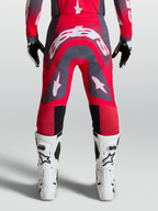 Alpinestars Supertech Hiten AFD, pantalon de motocross professionnel pour homme, rouge fluo et gris avec logos blancs, vue de dos montrant la coupe athlétique et les zones perforées pour la ventilation.