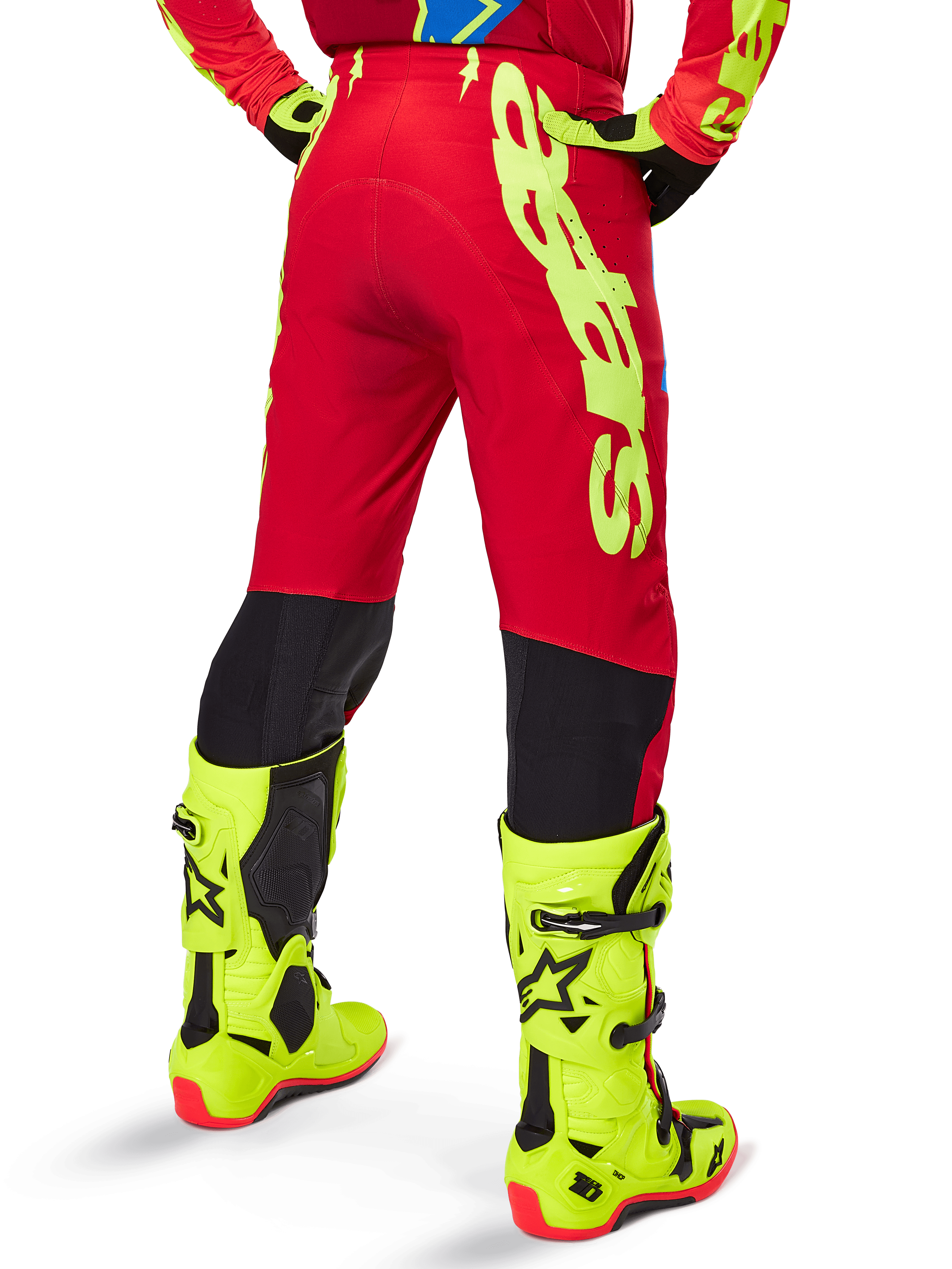 Alpinestars Supertech Maker Pants 2025, pantalon de motocross, rouge vif et jaune fluo, vue arrière, avec marquage jaune audacieux, panneaux noirs derrière les genoux, porté avec des bottes jaune fluo assorties, conçu pour des performances tout-terrain de niveau professionnel