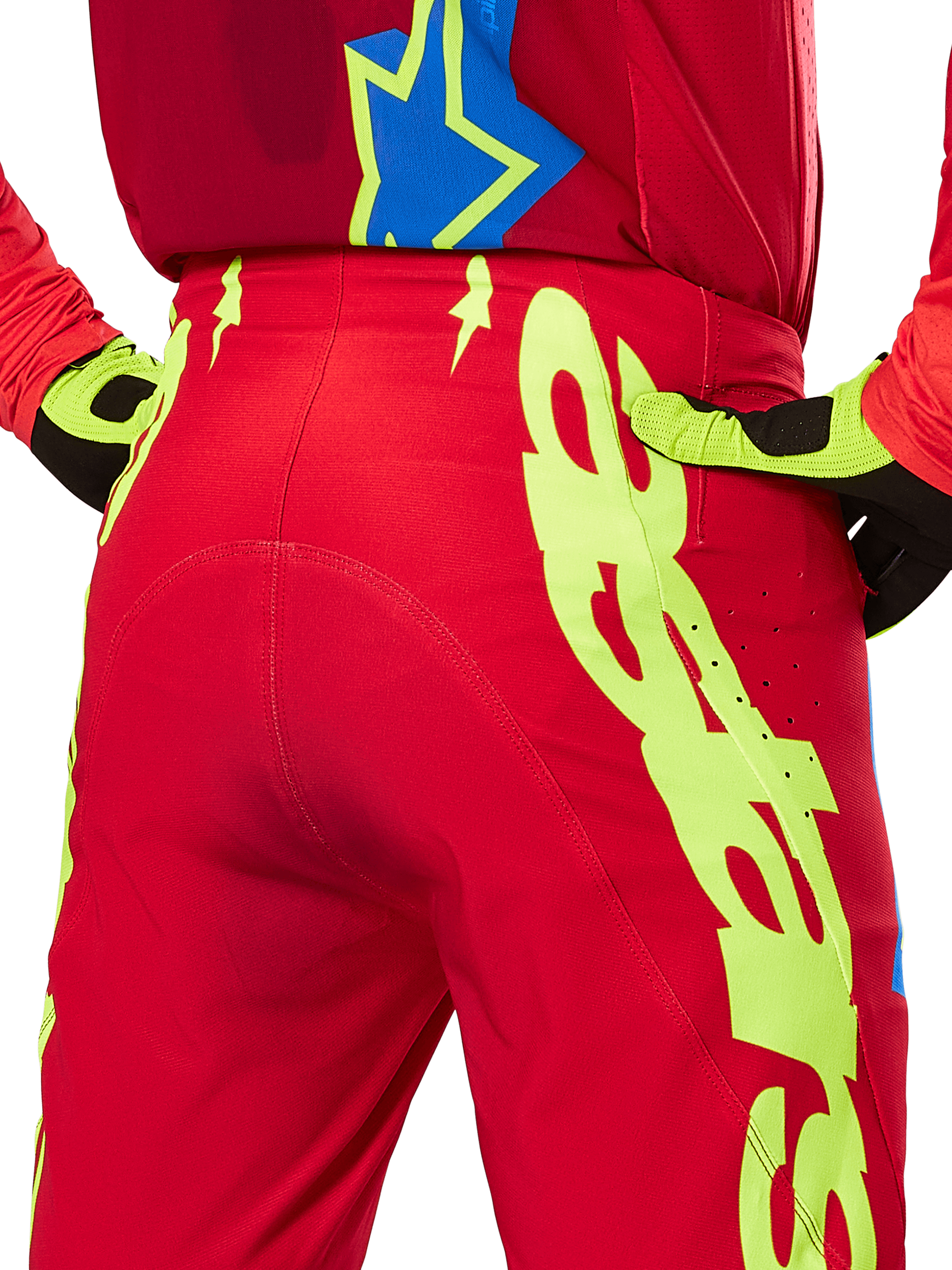 Alpinestars 2025 Supertech Maker Pants, pantalon de motocross, rouge vif et jaune fluo, gros plan arrière montrant des graphismes jaune fluo audacieux, porté avec un maillot rouge assorti et des gants jaune et noir