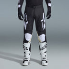 Ensemble d'équipement Alpinestars Racer Air Riway 2026, pantalon de motocross noir et blanc avec panneaux intérieurs aux genoux beiges, associé à des bottes de course blanches et des gants noirs, équipement de course tout-terrain léger et ventilé