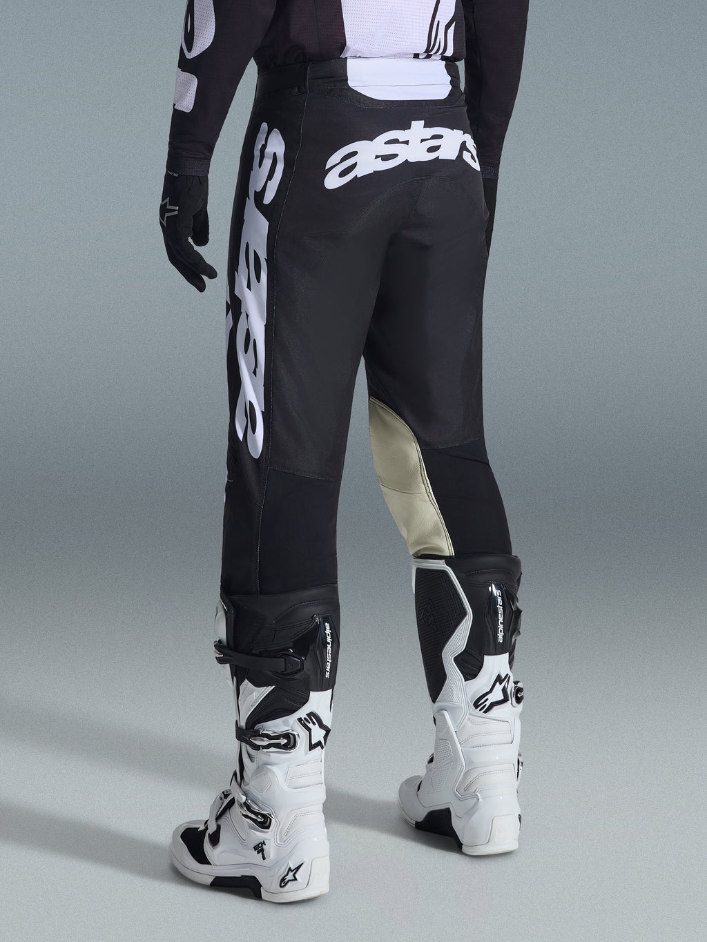 Pantalon de motocross Alpinestars Racer Air Riway 2026, vue arrière, noir et blanc, avec logo 'astars' blanc sur l'assise et la jambe, empiècements en cuir crème à l'intérieur des genoux, porté avec un maillot et des bottes assortis.