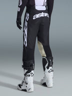Pantalon de motocross Alpinestars Racer Air Riway 2026, vue arrière, noir et blanc, avec logo 'astars' blanc sur l'assise et la jambe, empiècements en cuir crème à l'intérieur des genoux, porté avec un maillot et des bottes assortis.
