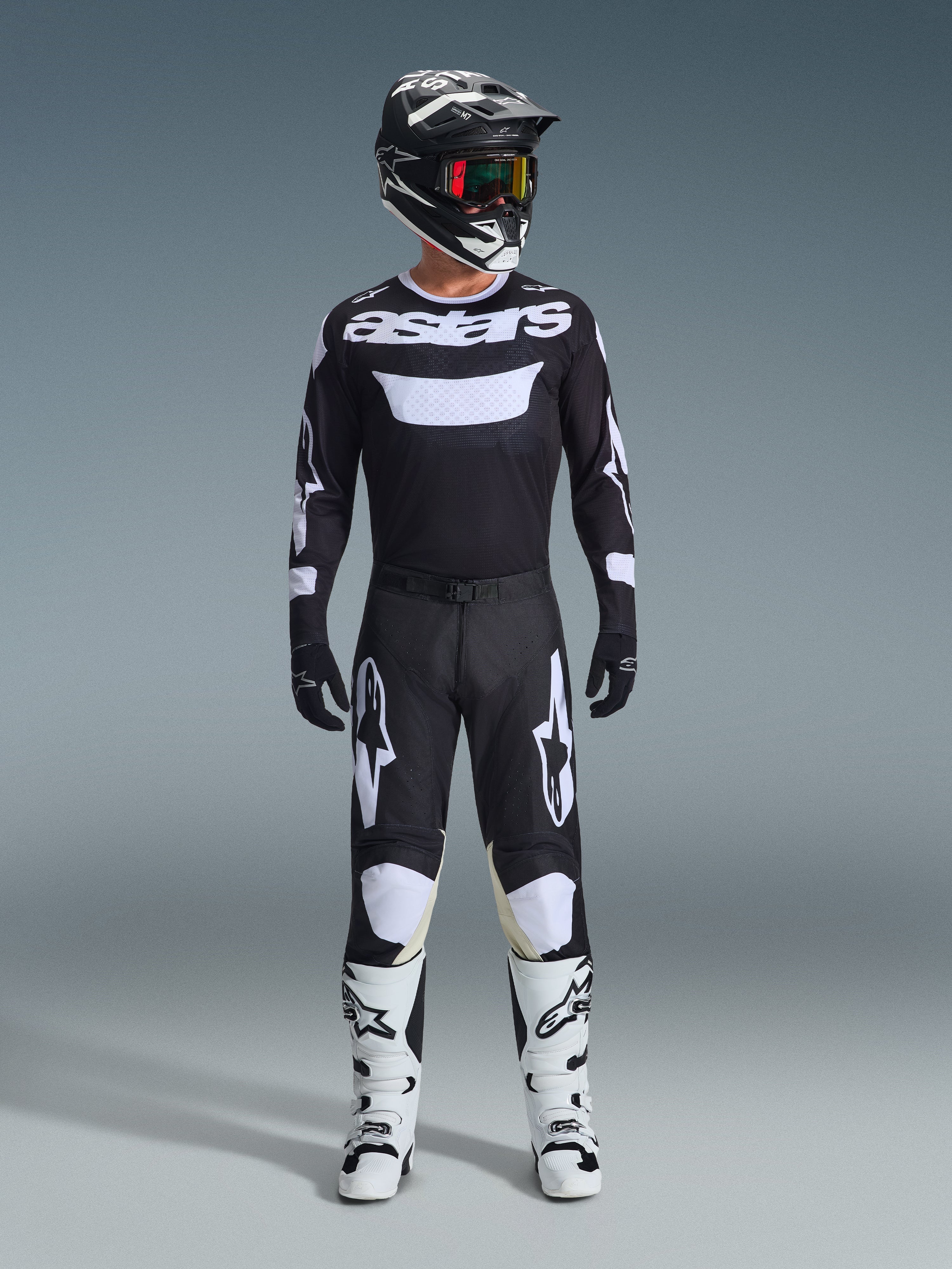 Ensemble d'équipement Alpinestars 2026 Racer Air Riway, tenue de motocross complète, noir et blanc, comprenant un maillot noir avec marquage « astars » blanc, un pantalon assorti avec empiècements blancs aux genoux, des bottes blanches avec boucles noires et un casque noir avec lunettes teintées rouge, équipement de course tout-terrain professionnel.