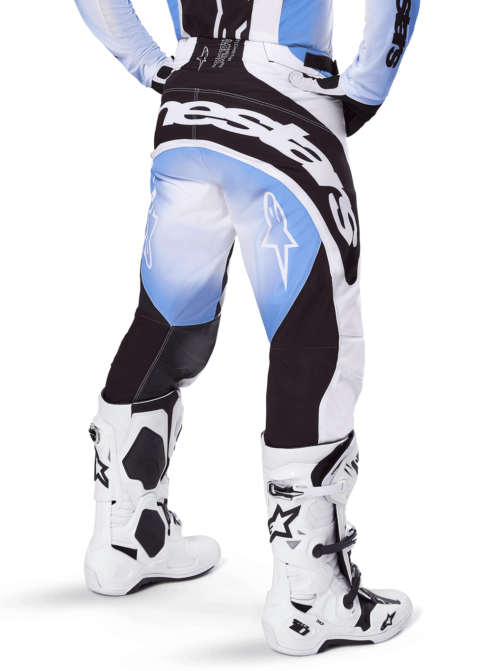 Alpinestars Pantalon Techstar Melt 2025, pantalon de motocross, noir, bleu et blanc, vue arrière avec logo Alpinestars imposant sur l'assise et logos étoiles sur les jambes, porté avec des bottes Tech 10 blanches et noires, équipement de course tout-terrain professionnel