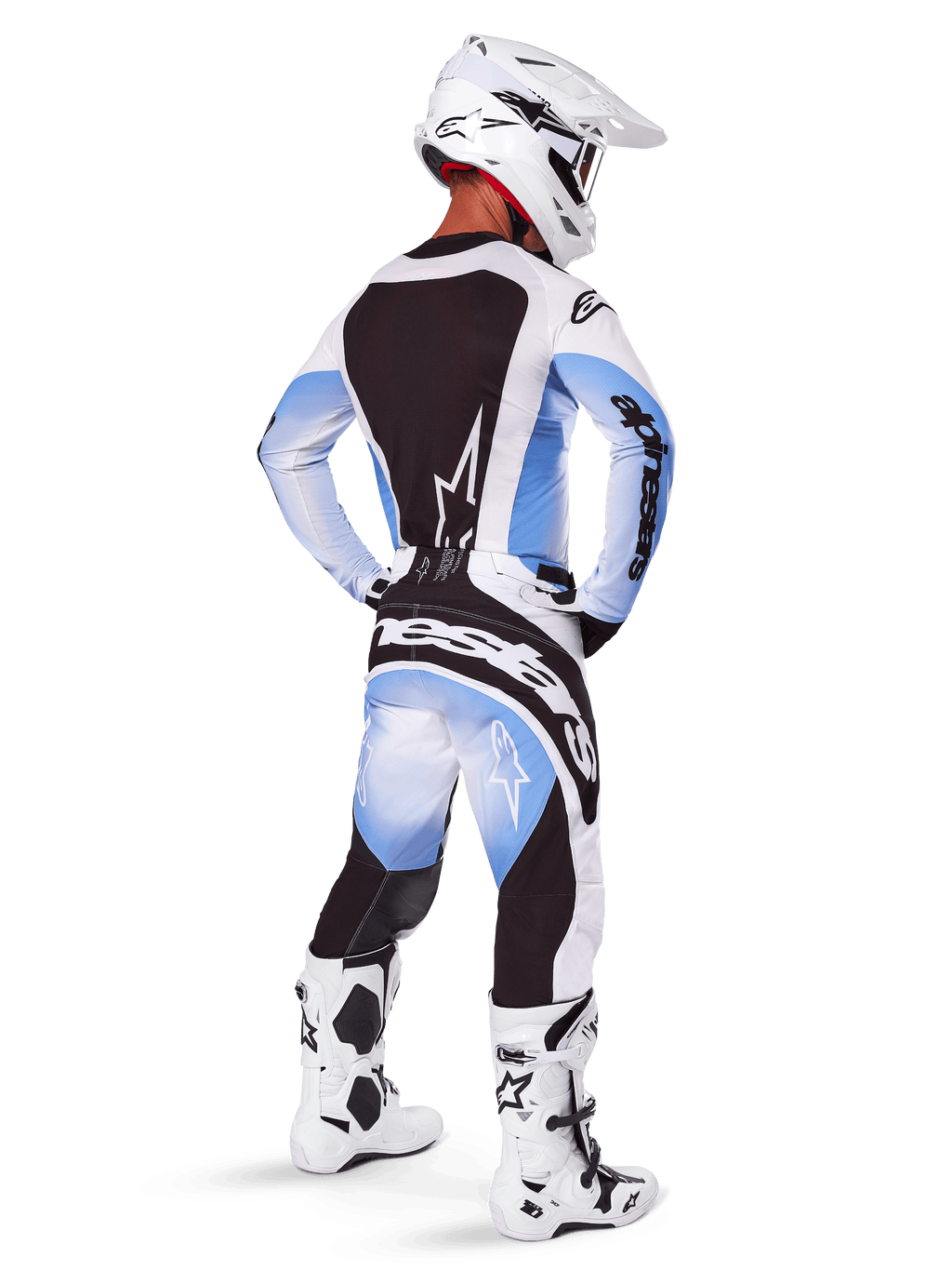 Pilote de motocross vu de dos portant le pantalon et le maillot Alpinestars 2025 Techstar Melt, design dégradé noir, bleu et blanc, casque blanc, bottes blanches et noires, tenue de course tout-terrain complète.