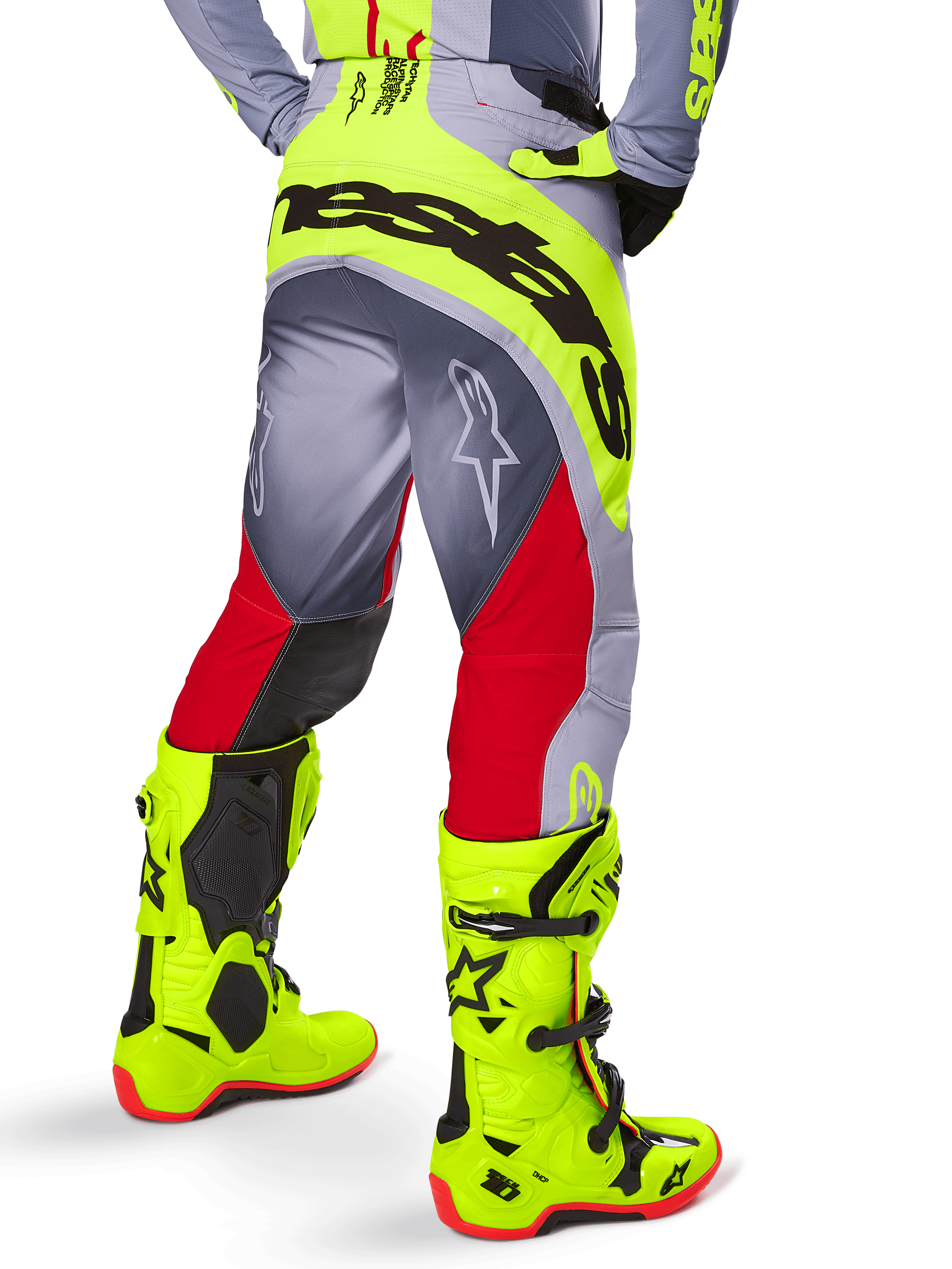 Alpinestars Techstar Melt Pants 2025, pantalon de motocross, rouge vif et gris avec des accents jaune fluo, vue arrière mettant en valeur le large logo noir sur l'assise, porté avec des bottes jaune fluo assorties et un maillot gris, coupe athlétique pour la compétition tout-terrain