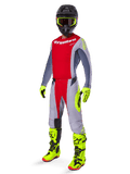 Pilote de motocross portant l'ensemble Alpinestars 2025 Techstar Melt, maillot et pantalon rouge et gris, gants et bottes jaune néon éclatant, casque noir, tenue de course tout-terrain complète