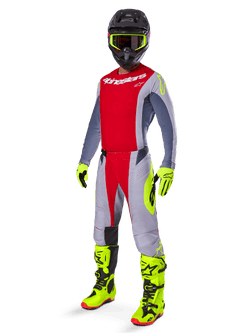 Motocross rider wearing the Alpinestars 2025 Techstar Melt Gear Set, red and gray jersey and pants, vibrant neon yellow gloves and boots, black helmet, complete off-road racing kit