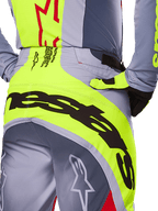 Alpinestars Techstar Melt Pants 2025, gros plan sur l'assise et la zone de la taille, design gris et jaune fluo avec large marquage noir, logos étoiles et texte technique, équipement de motocross haute performance