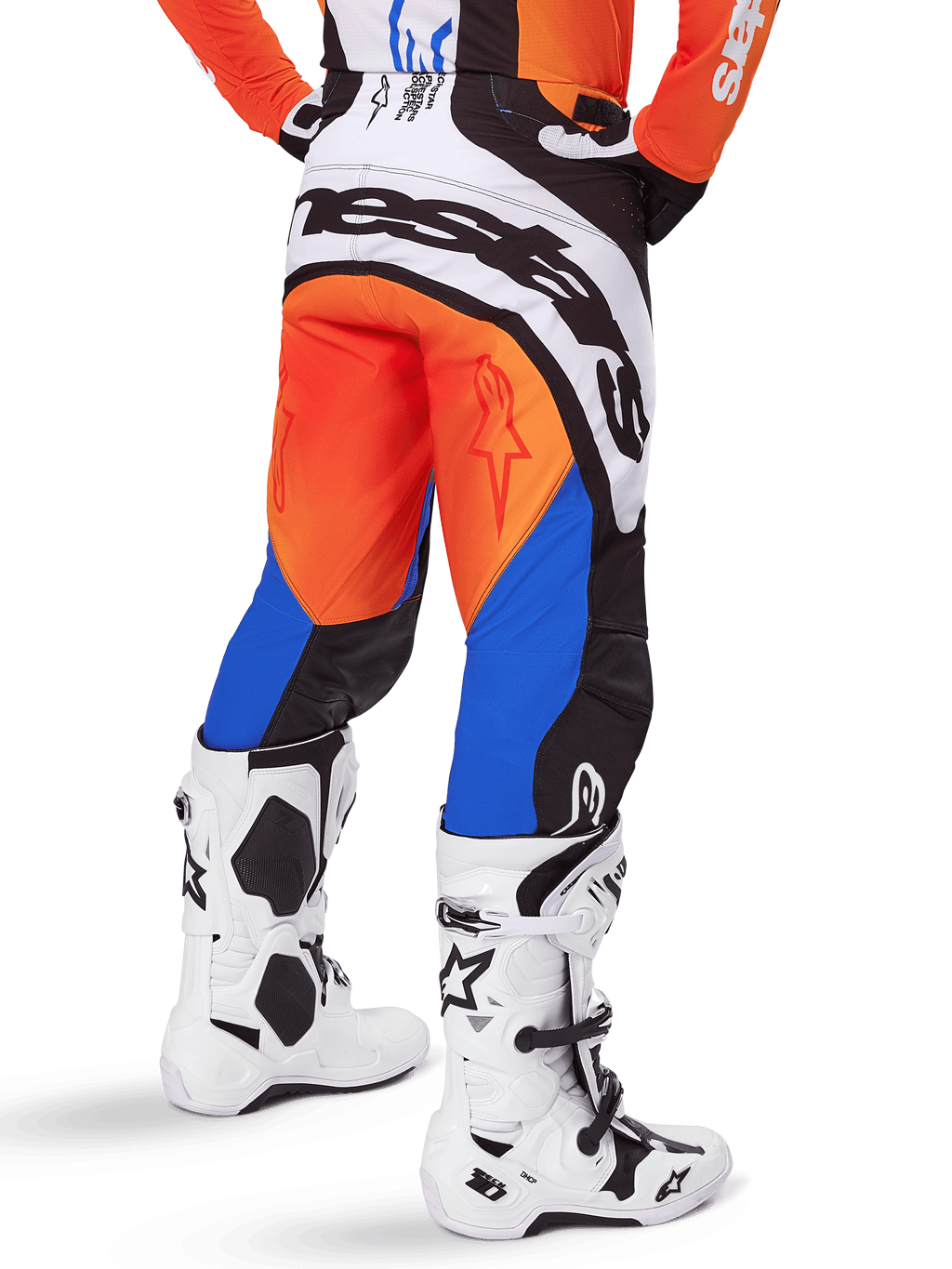 Pantalon Alpinestars Techstar Melt 2025, pantalon de motocross, orange et bleu, vu de dos, avec un grand logo blanc sur l'assise, porté avec un maillot orange assorti et des bottes Tech 10 blanches, équipement de course tout-terrain durable
