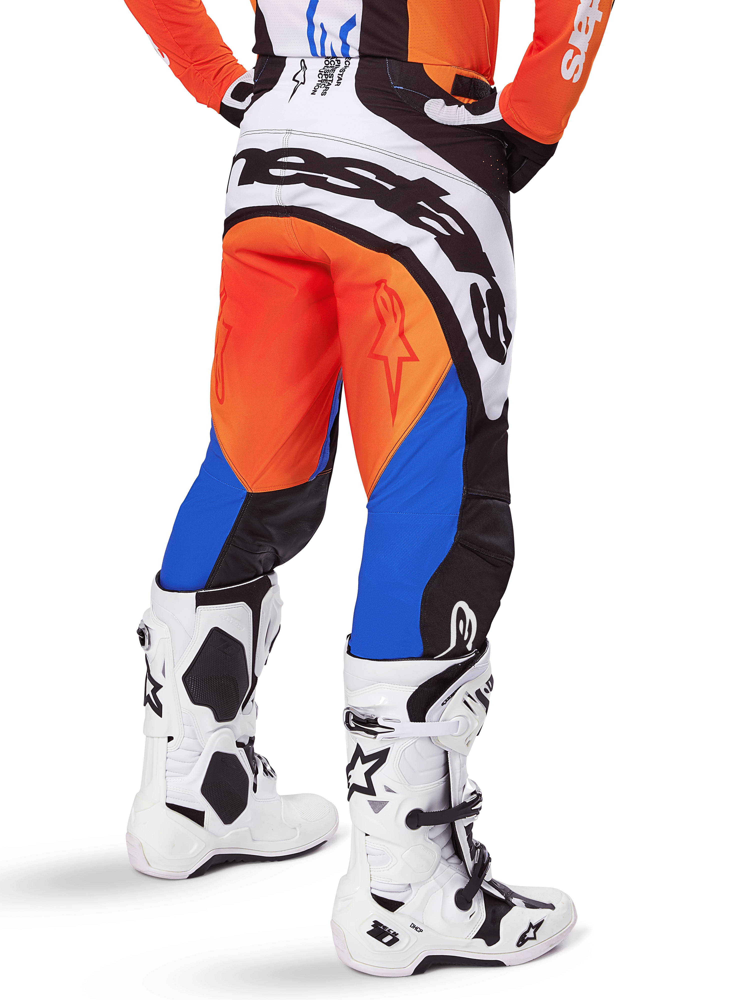 Pantalon Alpinestars Techstar Melt 2025, pantalon de motocross, orange et bleu, vu de dos, avec un grand logo blanc sur l'assise, porté avec un maillot orange assorti et des bottes Tech 10 blanches, équipement de course tout-terrain durable
