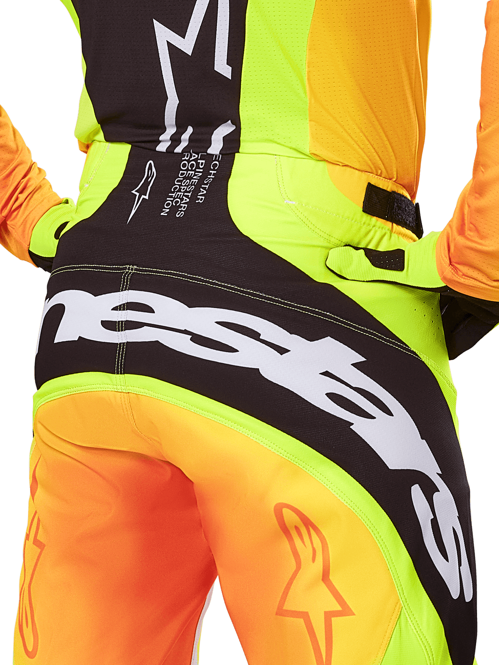 Pantalon Alpinestars Techstar Melt 2025, pantalon de motocross, vue arrière en gros plan, jaune fluo et orange avec empiècements noirs, grand logo Alpinestars blanc sur l'assise, équipement de performance pour le tout-terrain