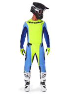 Alpinestars 2025 Techstar Melt Pants, pantalon de motocross, jaune fluo et bleu, porté avec un maillot assorti, des gants jaunes et des bottes blanches et noires, avec un casque noir et des lunettes rouges, ensemble complet d'équipement de course pour la performance tout-terrain
