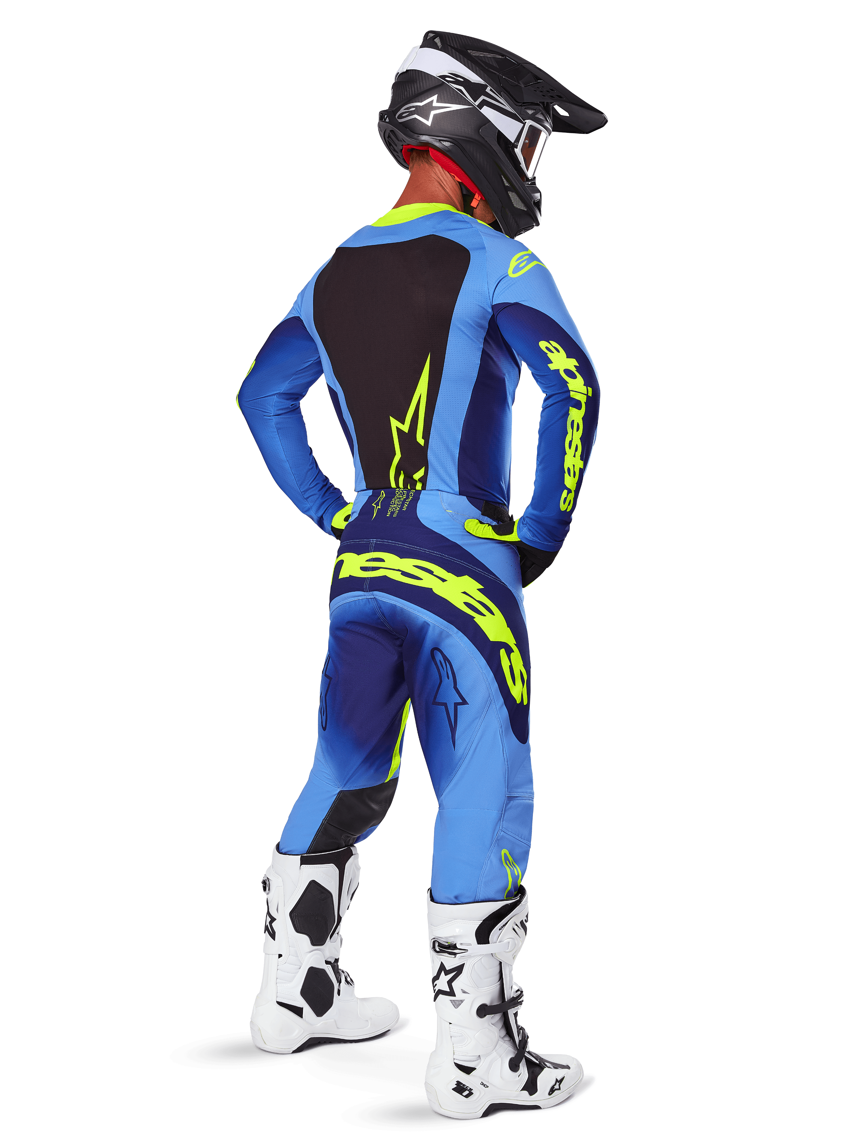 Alpinestars Techstar Melt Pants 2025, équipement de motocross, jaune fluo et bleu, vue arrière du pilote portant un maillot bleu assorti avec un large marquage jaune, des bottes blanches et noires et un casque noir, tenue de course coordonnée pour la performance tout-terrain
