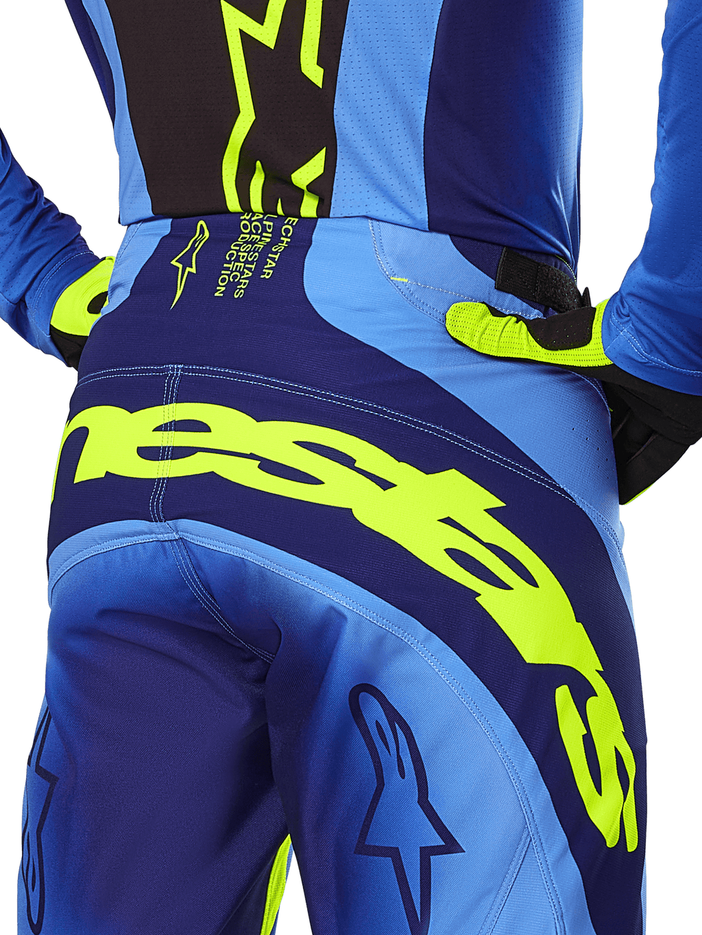 Alpinestars Techstar Melt Pants 2025, pantalon de motocross, jaune fluo et bleu, vue arrière rapprochée avec logo Alpinestars jaune sur l'assise, porté avec maillot et gants assortis, équipement de performance pour la course tout-terrain