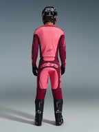 Motocross rider from the back wearing the Alpinestars 2026 Racer Riway Jersey and matching pants in Dark Red Coral, featuring black boots, a black helmet, and black gloves, coordinated high-performance gear for off-road racing