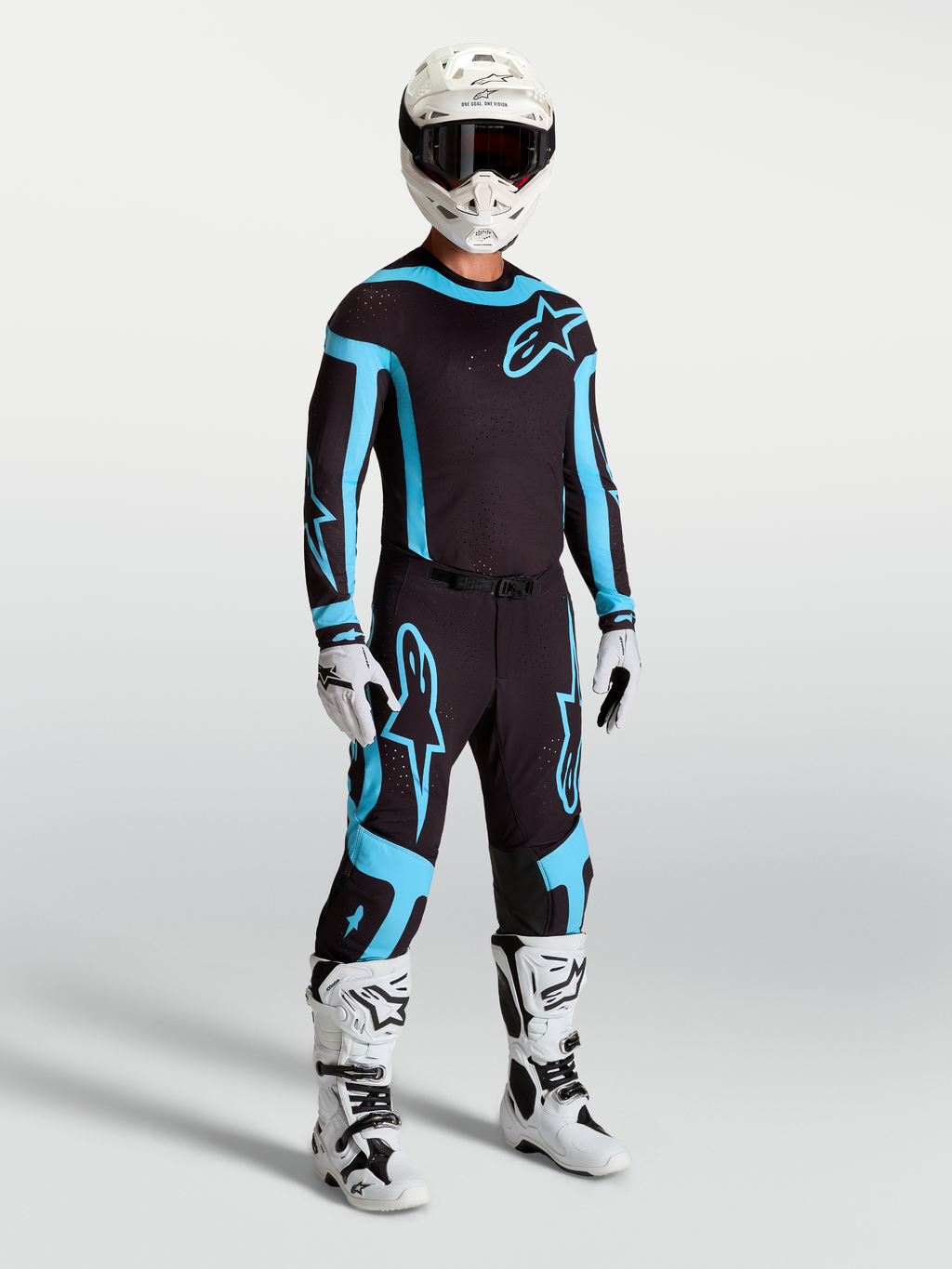 Pantalon Alpinestars Supertech Vesta, équipement de motocross pour homme, noir et turquoise, avec bottes et casque blancs.