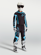 Pantalon Alpinestars Supertech Vesta, équipement de motocross pour homme, noir et turquoise, avec bottes et casque blancs.