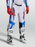 Alpinestars Pantalons Supertech Vesta, équipement de motocross blancs et rouges avec graphismes d'étoiles bleues, coupe athlétique sur mannequin.