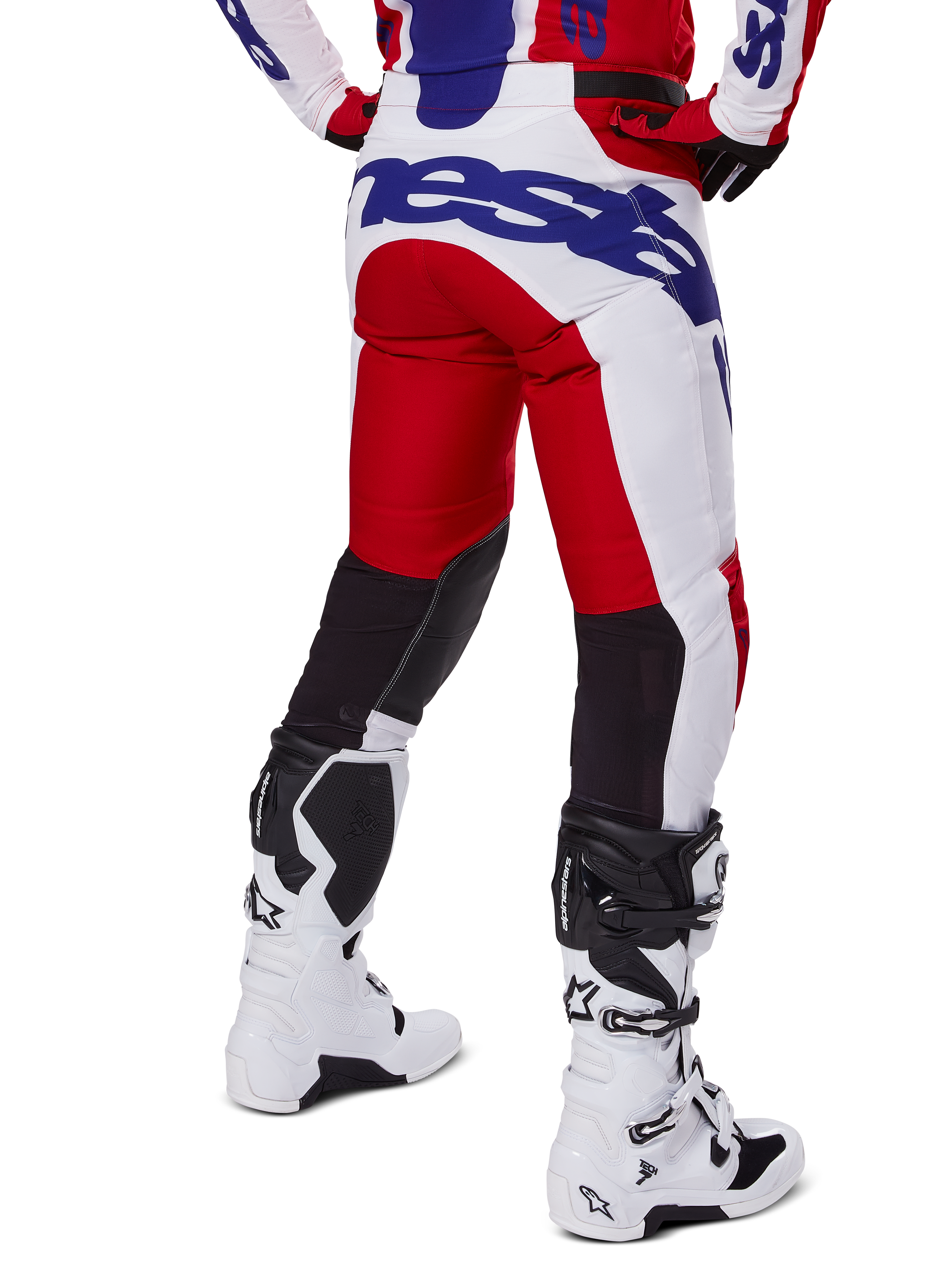 Alpinestars 2025 Racer Veil Pants, pantalon de motocross, rouge vif et blanc avec logo bleu, vue arrière montrant des empiècements de ventilation noirs extensibles à l'arrière des jambes, associé à des bottes de motocross blanches