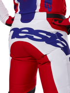 Alpinestars 2025 Racer Veil Pants, pantalon de motocross, rouge vif et blanc avec logo bleu, vue arrière détaillée de l'assise présentant un grand logo Alpinestars, porté dans le cadre d'une tenue de course tout-terrain coordonnée