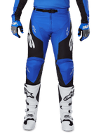 Alpinestars 2025 Racer Veil Pants, Motocross Pants, Blue and Black, featuring white Alpinestars logos on the legs, black side panels, worn with white motocross boots and blue/grey gloves, high-performance off-road riding gear