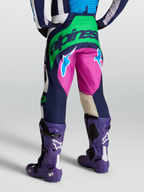 Alpinestars Pantalon Techstar Maven, équipement motocross bleu et vert, vue arrière avec bottes Tech 10 violettes.