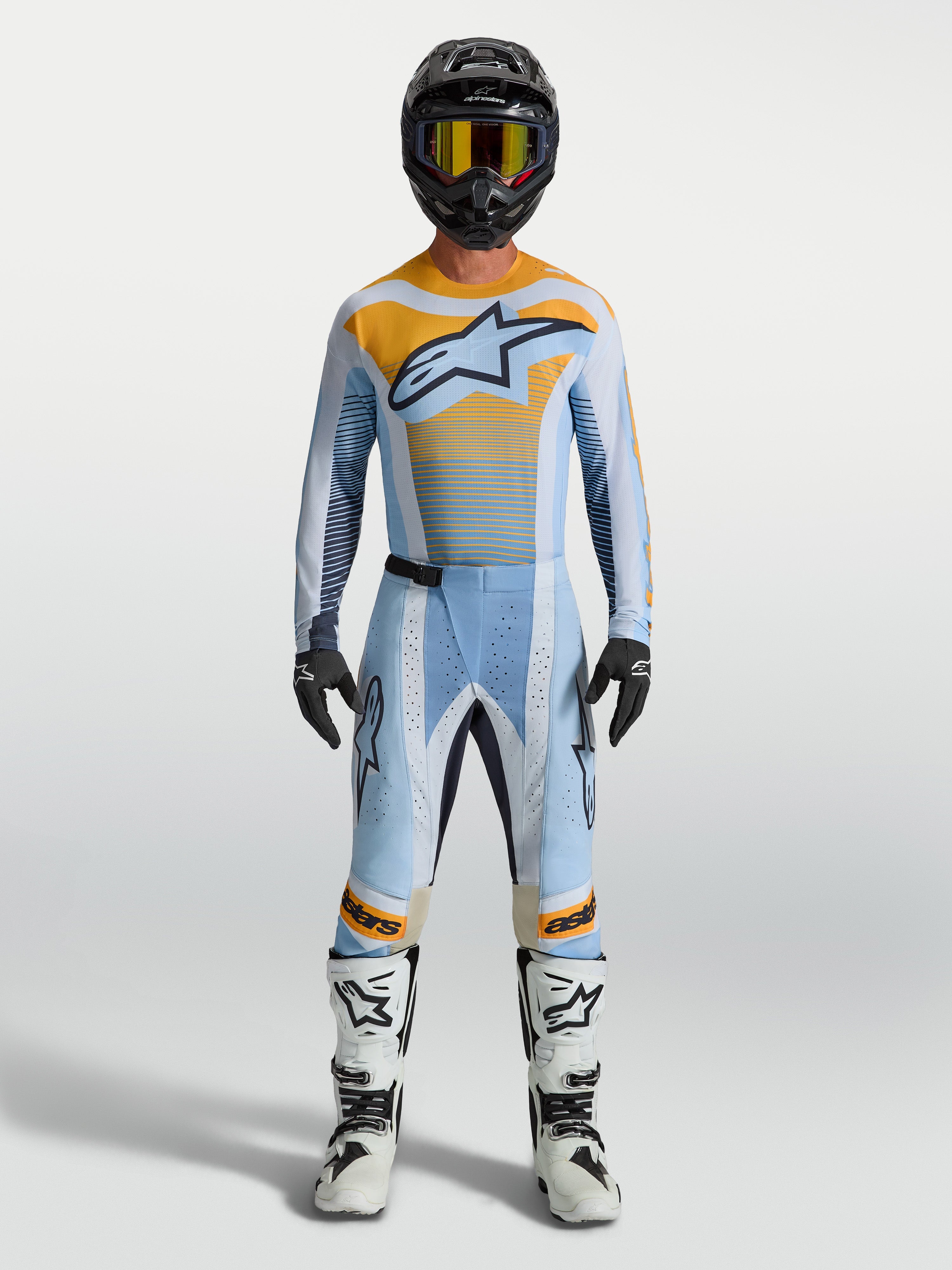 Pantalon Alpinestars Techstar Maven, motocross pour homme, bleu et orange, porté par un pilote, coupe de course, zones extensibles.