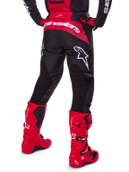 Set d'équipement Alpinestars Fluid Haul 2025, vue arrière, pantalon de motocross noir et rouge avec de grands logos blancs, maillot assorti et bottes Tech 7 rouge vif, tenue de course tout-terrain coordonnée