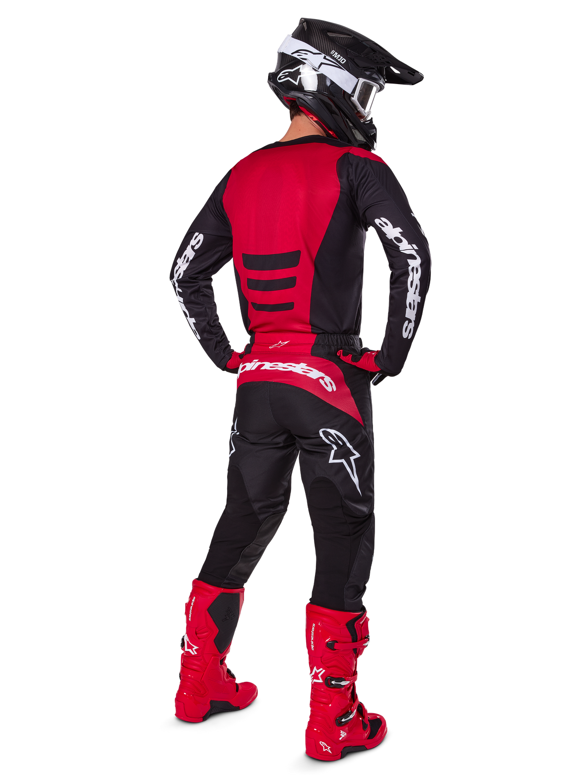 Pilote de motocross portant l'ensemble d'équipement Alpinestars 2025 Fluid Haul vu de dos, maillot rouge et noir avec marquage blanc, pantalon noir assorti avec accents rouges, bottes rouge vif et casque noir avec lunettes blanches, tenue coordonnée complète pour la course tout-terrain