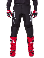 Ensemble d'équipement Alpinestars 2025 Fluid Haul, pantalon de motocross noir avec logos Astars blancs sur les cuisses, associé à des bottes rouges éclatantes et des gants rouges et noirs, tenue de motocross coordonnée pour la course tout-terrain