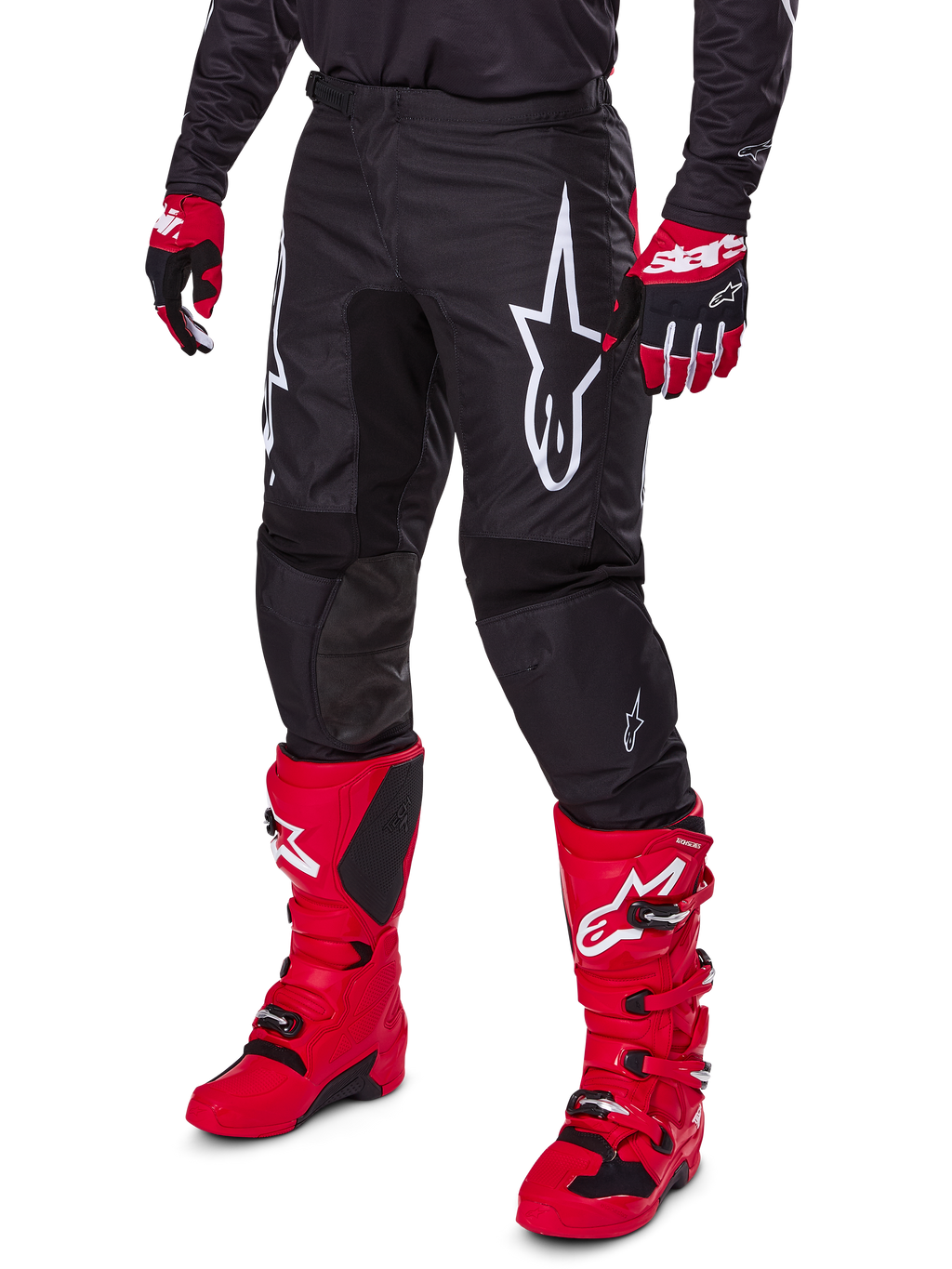 Alpinestars 2025 Fluid Haul Pants, pantalon de motocross, noir, avec un grand logo Alpinestars blanc, porté avec des bottes rouge vif et des gants rouges et noirs, construction durable en poly-tissu 600D avec coupe ergonomique pour la course tout-terrain