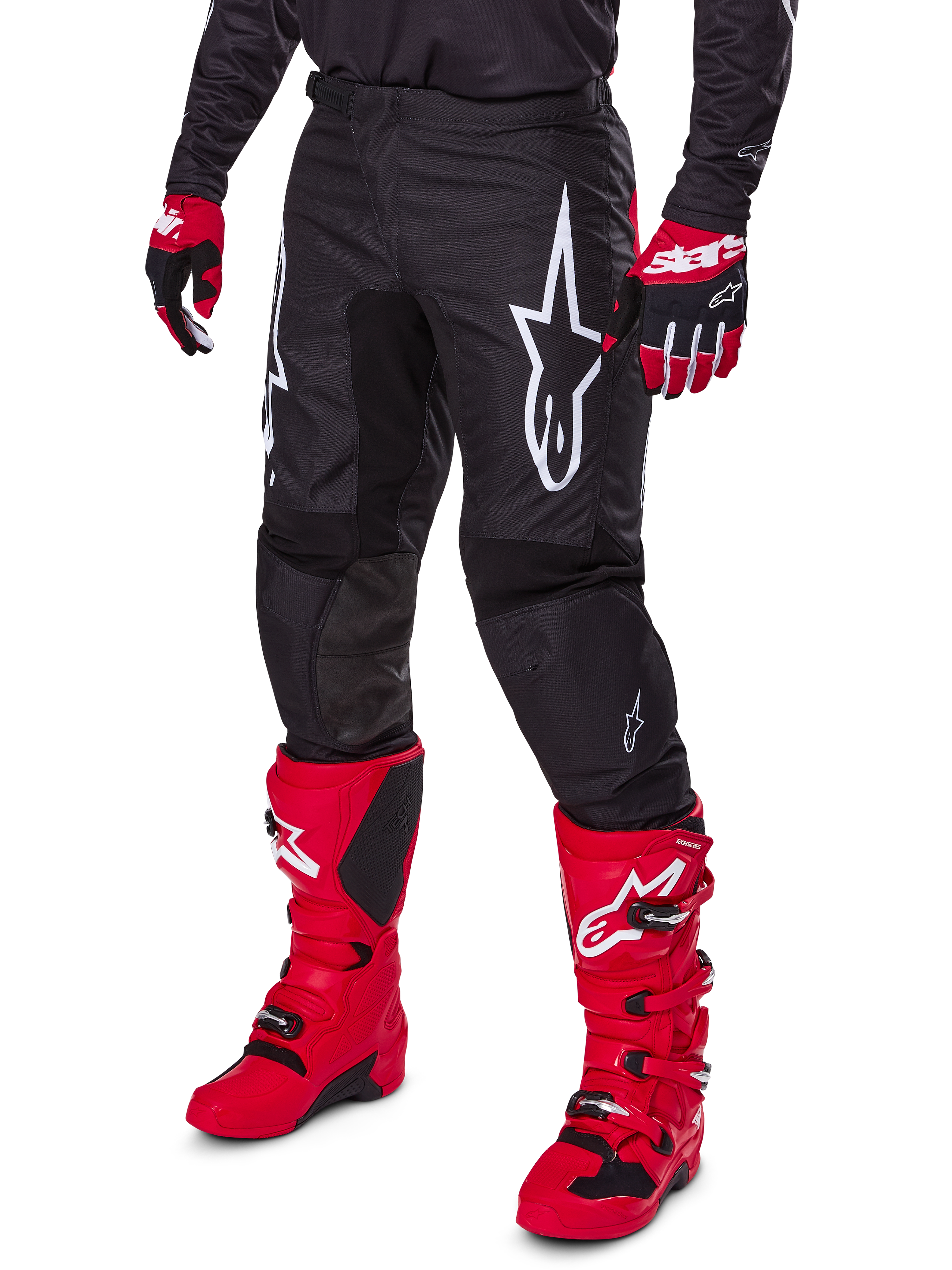 Alpinestars 2025 Fluid Haul Pants, pantalon de motocross, noir, avec un grand logo Alpinestars blanc, porté avec des bottes rouge vif et des gants rouges et noirs, construction durable en poly-tissu 600D avec coupe ergonomique pour la course tout-terrain