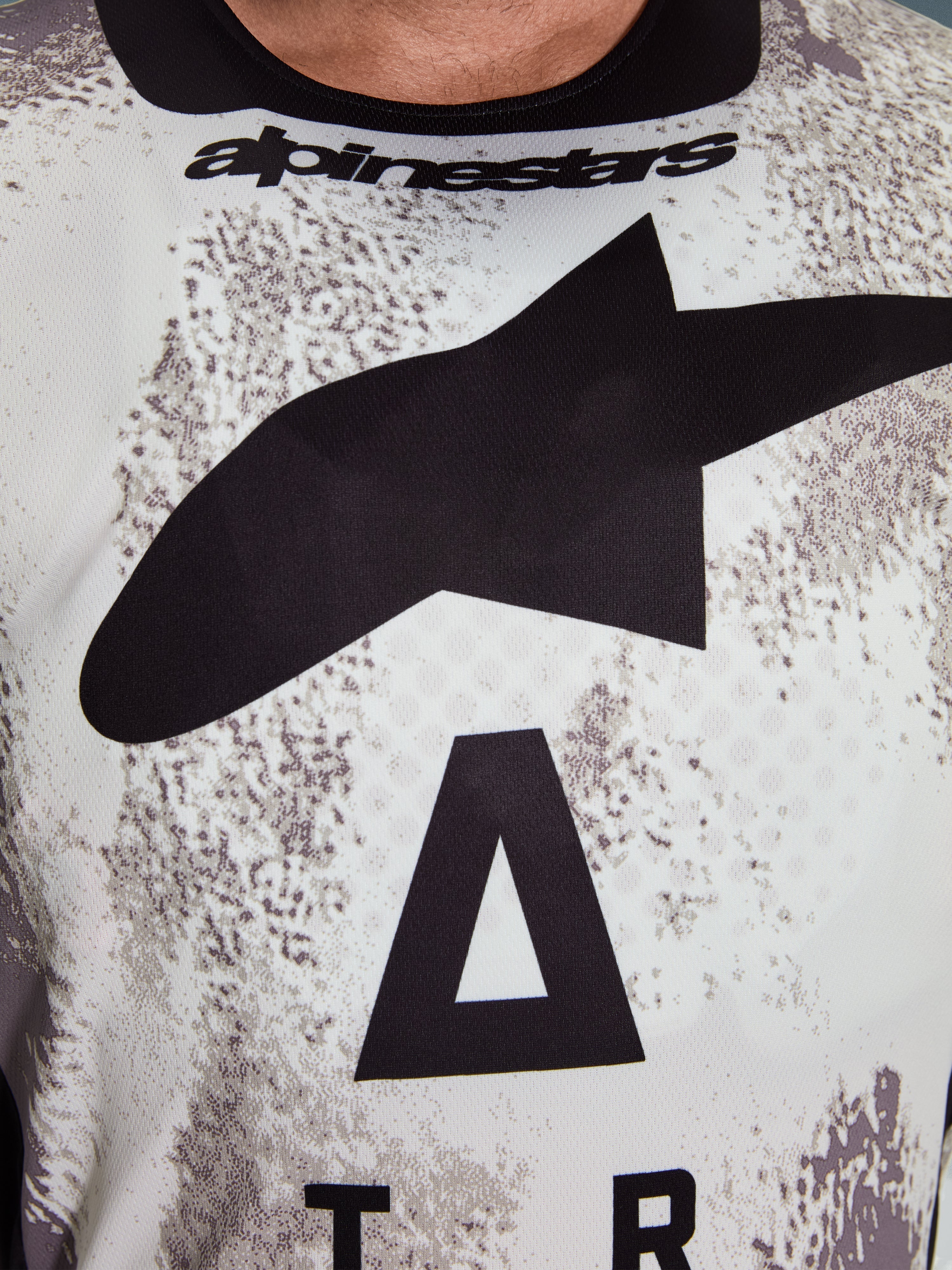 Alpinestars 2026 Racer Lahnd Jersey, close-up of chest area, Sand Camo pattern with large black star logo and Alpinestars wordmark, breathable performance polyfabric for off-road riding