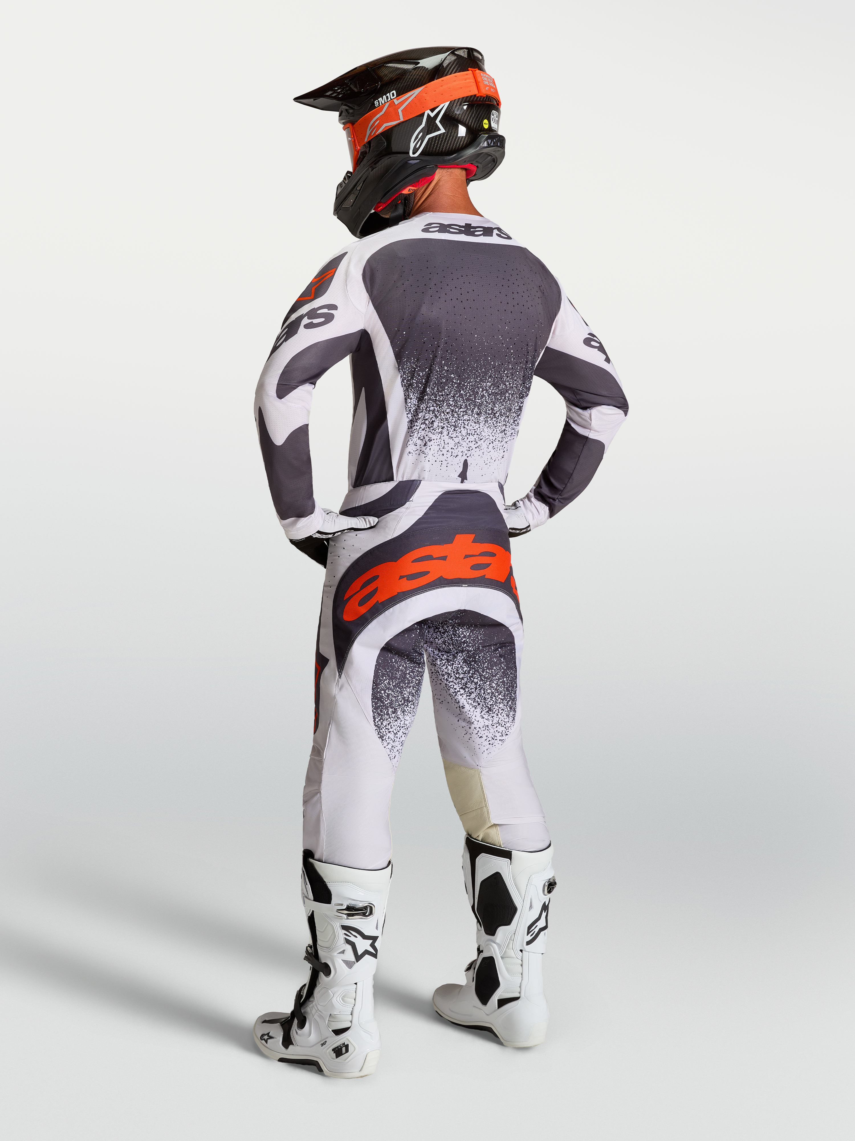 Ensemble Alpinestars Techstar Swan, maillot et pantalon de motocross pour homme, gris, blanc et rouge fluo, vue de dos.