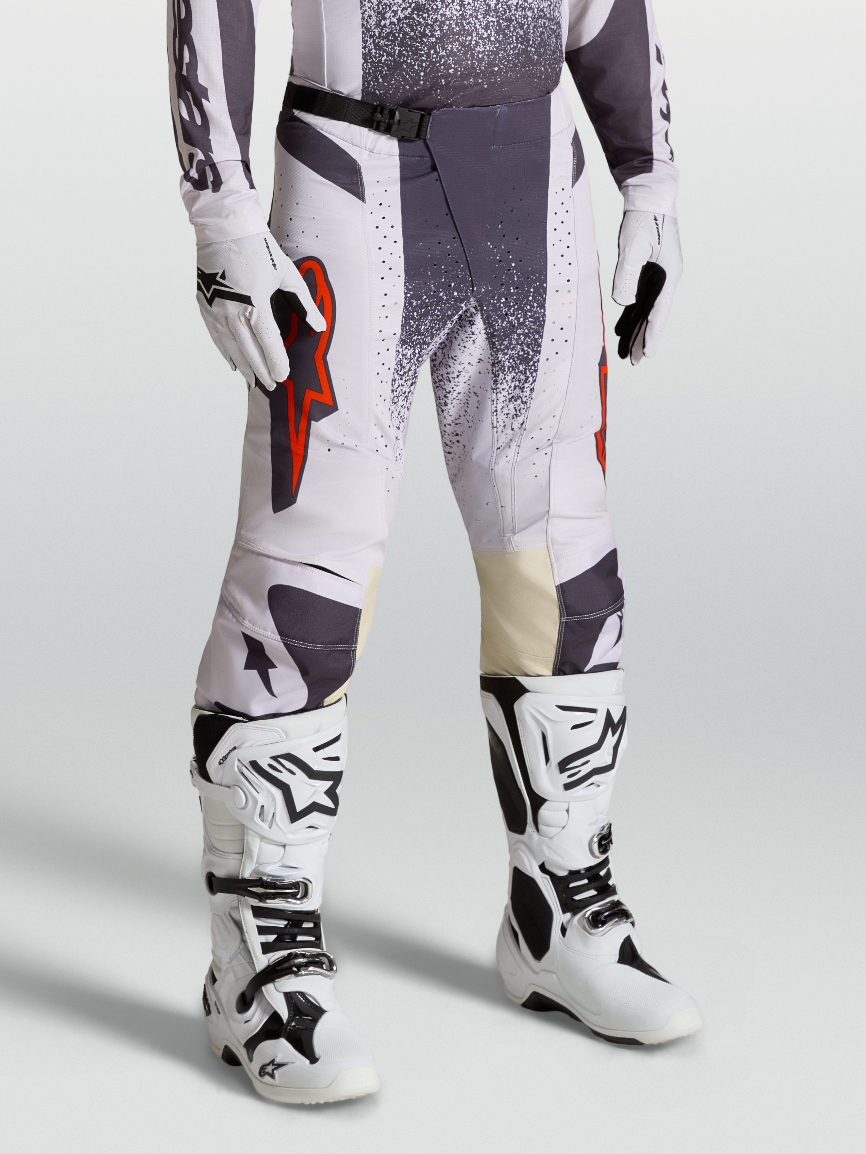 Alpinestars Pantalon Techstar Swan, pantalon de motocross pour homme, lilas clair et gris foncé avec accents rouge fluo, porté avec gants et bottes assortis