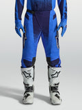 Alpinestars Pantalon Techstar Swan, équipement de motocross pour homme, bleu clair et bleu foncé, avec panneaux extensibles perforés, porté avec des bottes blanches