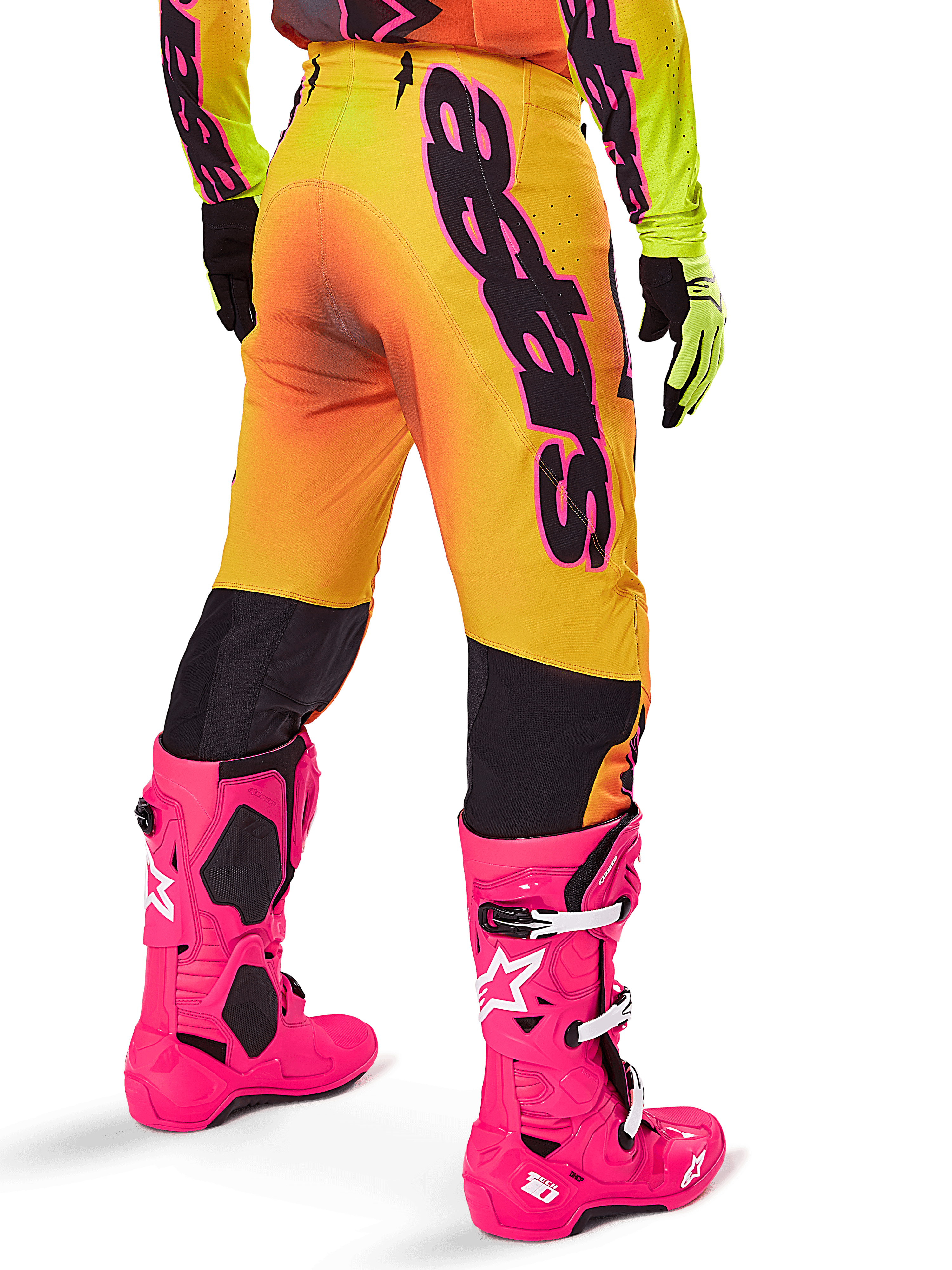 Ensemble d'équipement Alpinestars Supertech Lipan 2025, vue arrière du pantalon de motocross avec dégradé jaune et orange et marquage noir imposant, associé à des bottes Tech 10 rose vif et des gants jaunes, équipement de course tout-terrain professionnel