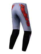 Alpinestars Supertech Lipan Pants 2025, pantalon de motocross, gris et orange fluo, vue arrière avec empiècements noirs au bas des jambes et grands logos Alpinestars orange sur les hanches, coupe athlétique pour la course tout-terrain