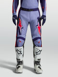 Alpinestars Racer Air Hunt, pantalons de motocross violets et rose fluo, portés avec des bottes blanches