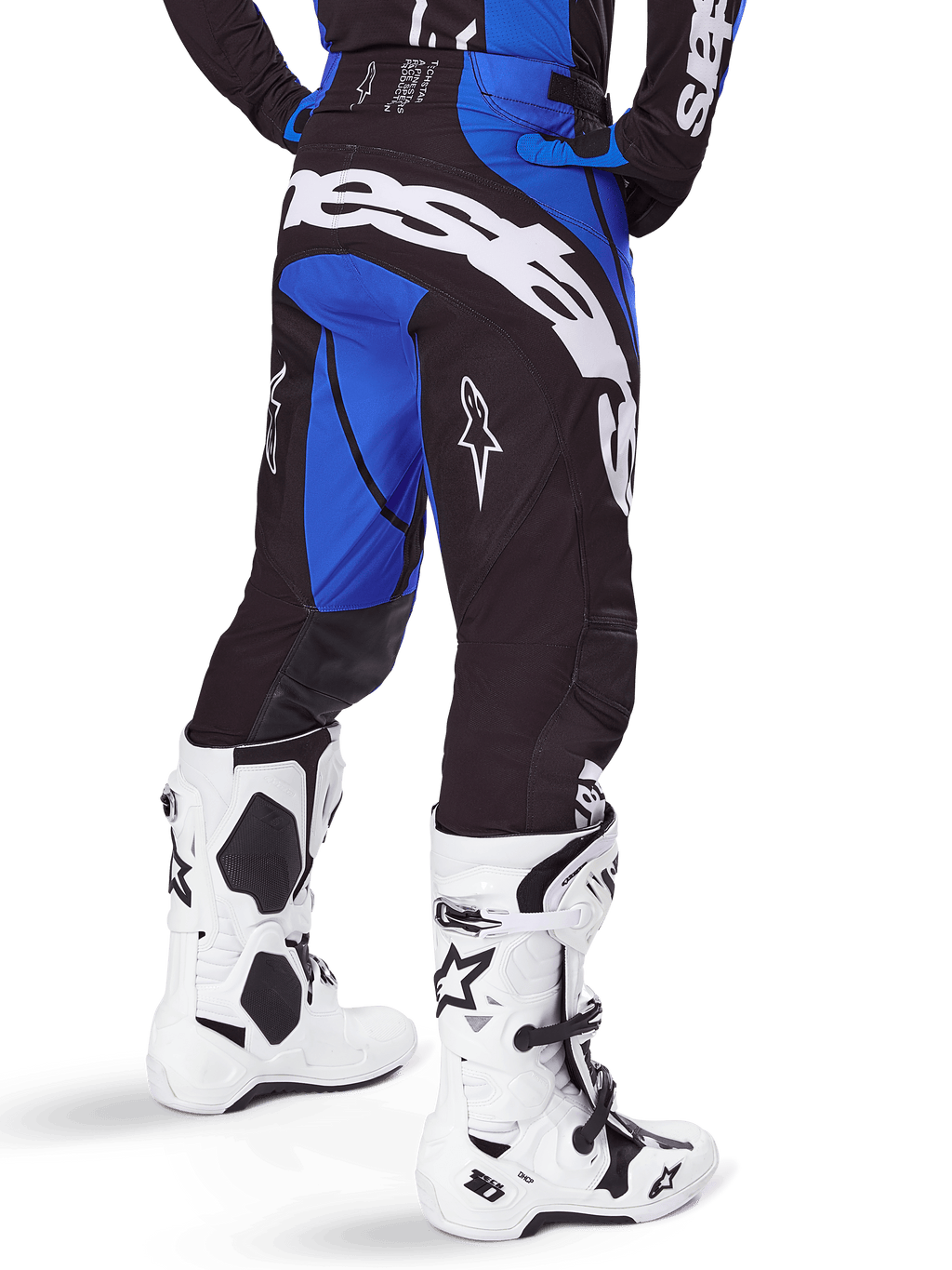 Alpinestars Techstar Dreem Pants 2025, pantalon de motocross, noir et bleu, vue arrière montrant le marquage Alpinestars blanc sur l'assise, porté avec des bottes de motocross blanches et noires et un maillot bleu assorti, coupe athlétique pour la course tout-terrain