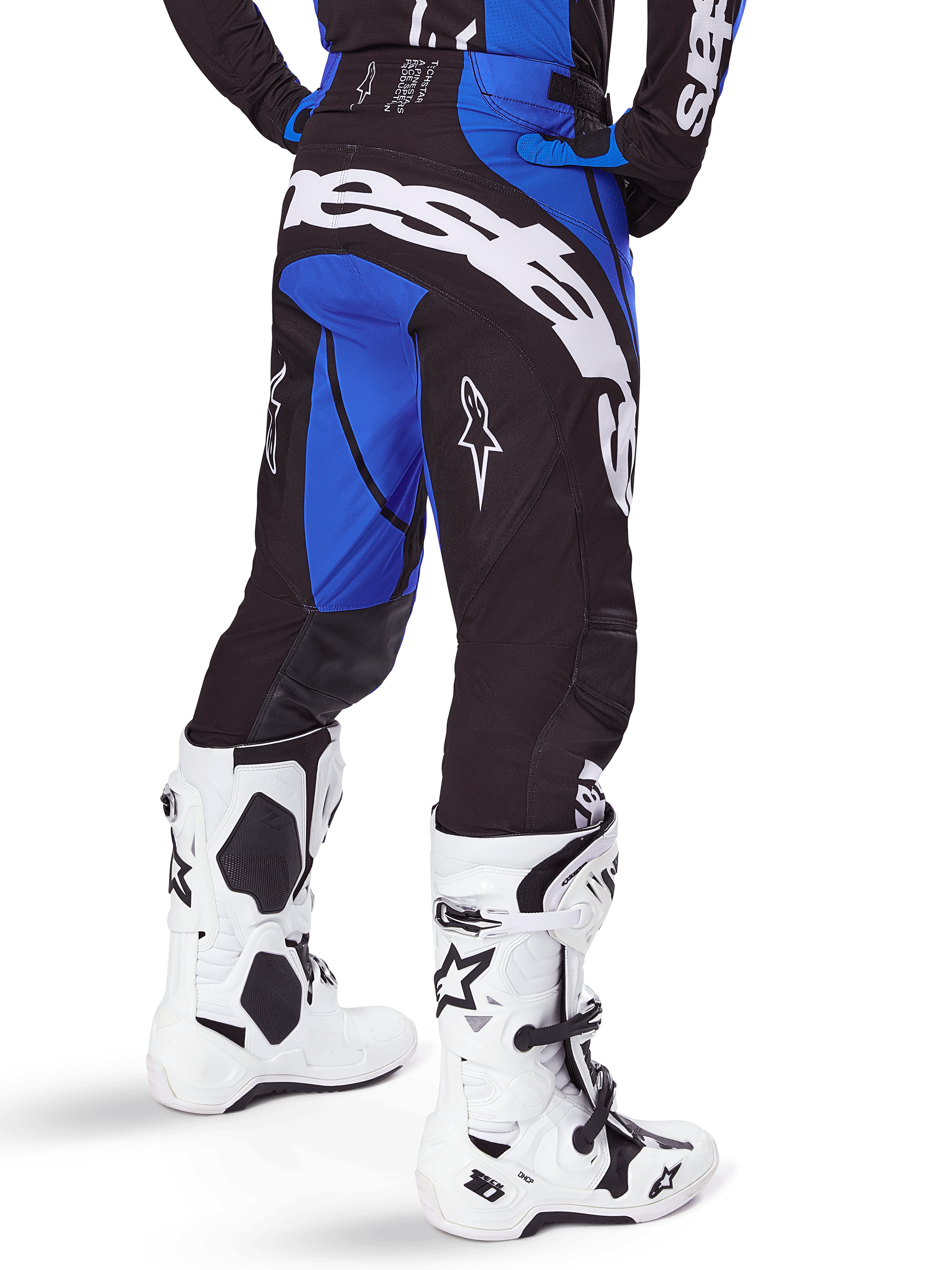 Alpinestars Techstar Dreem Pants 2025, pantalon de motocross, noir et bleu, vue arrière montrant le marquage Alpinestars blanc sur l'assise, porté avec des bottes de motocross blanches et noires et un maillot bleu assorti, coupe athlétique pour la course tout-terrain