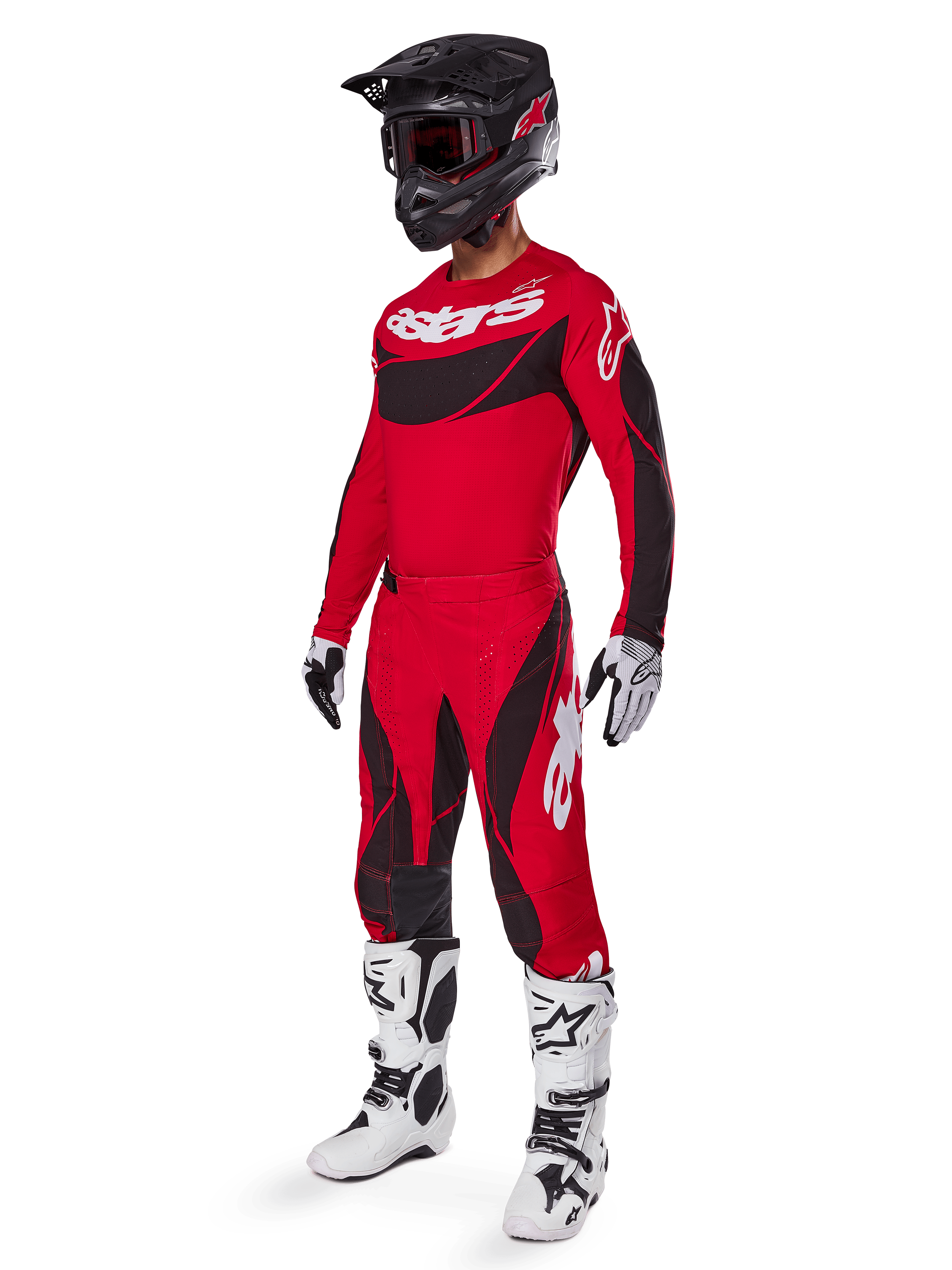 Pilote de motocross portant une tenue de course complète comprenant le pantalon Alpinestars Techstar Dreem 2025 rouge vif et noir, un maillot assorti rouge et noir avec logo blanc, un casque noir et des bottes blanches et noires, tenue coordonnée pour la course tout-terrain