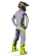 Pilote de motocross vu de dos portant un équipement de course complet, comprenant le pantalon Alpinestars Techstar Dreem 2025 gris et gris foncé avec des accents jaune néon vifs, un maillot gris assorti avec des graphismes néon, des bottes jaune néon éclatantes et un casque noir, tenue de motocross professionnelle coordonnée