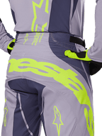 Alpinestars 2025 Techstar Dreem Pants, pantalon de motocross, gris et gris foncé avec accents jaune fluo, vue arrière montrant le marquage Alpinestars imposant sur l'empiècement, porté avec le maillot et les gants assortis, conçu pour la course tout-terrain
