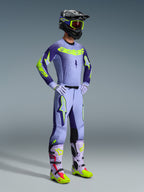 Alpinestars 2026 Supertech Scenz Pants, Motocross Pants, Purple and Yellow Fluo, worn by a rider in a complete racing outfit with a matching gradient jersey, lilac gloves, and coordinated yellow and purple boots, featuring a black helmet and goggles.