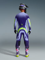 Motocross rider from behind wearing Alpinestars 2026 Supertech Scenz Pants in Purple Yellow Fluo, matching jersey with gradient purple and neon yellow graphics, black helmet, and purple boots, coordinated professional racing gear for off-road performance